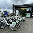 E-Bike Verleihstation Bergisch Gladbach Leihfahrräder vor einer modernen Radstation auf gepflastertem Platz, umgeben von Büros und Wolken.