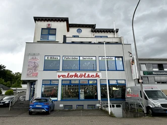 Velokölsch Fahrradladen mit großer Glasfassade und blauem Schriftzug "velokölsch", Angebot: E-Bikes, Zubehör.