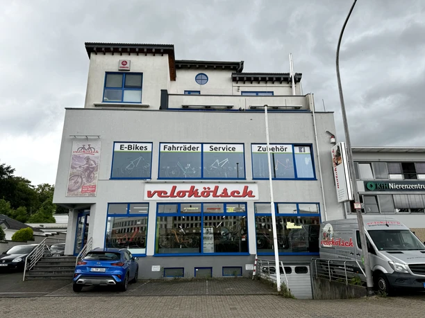 Velokölsch Fahrradladen mit großer Glasfassade und blauem Schriftzug "velokölsch", Angebot: E-Bikes, Zubehör.