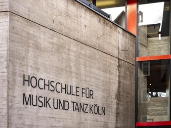 University of Music and Dance Außenansicht der modernen Architektur der Hochschule für Musik und Tanz Köln mit Betonwänden und roten Fensterrahmen.Exterior view of the modern architecture of the Cologne University of Music and Dance with concrete walls and red window frames.