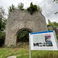 Kalköfen Ruine eines alten, von der Natur überwucherten Steinbaus mit Informationstafel im Vordergrund.