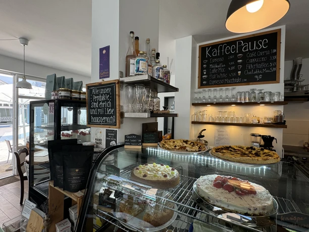 Kaffeepause - Innenansicht Konditorei mit Kuchenauswahl, Spirituosen und Getränkekarte, helle Innenraumgestaltung.