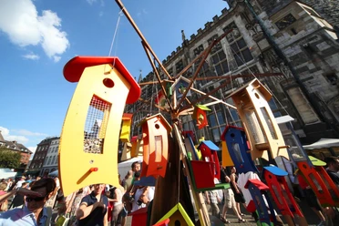 Vor dem Aachener Rathaus steht ein Stand mit bunt angemalten Vogelhäusern aus Holz.