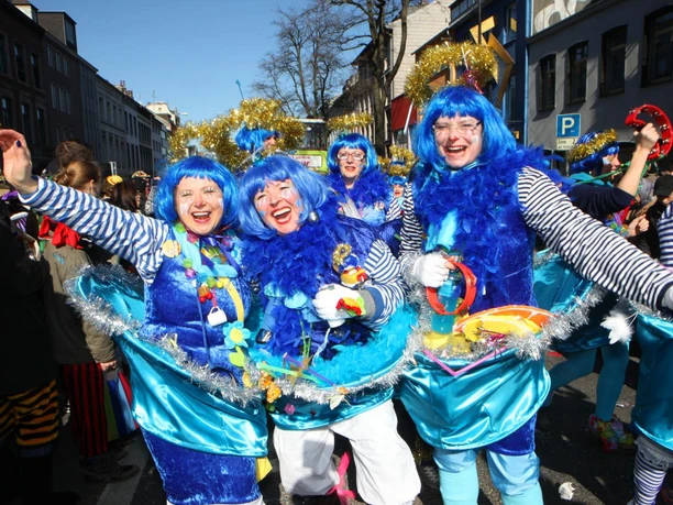 Rosenmontagszug Aachen Gruppe in bunten Karnevalskostümen mit blauen Perücken beim fröhlichen Rosenmontagszug in Aachen.