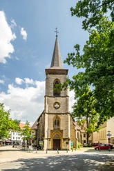 Süsterkirche Bielefeld Historische Kirche mit hohem Turm, umgeben von Bäumen und blauem Himmel in urbanem Umfeld.