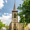 Süsterkirche Bielefeld Historische Kirche mit hohem Turm, umgeben von Bäumen und blauem Himmel in urbanem Umfeld.