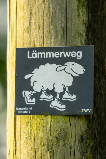 Wegezeichen Bielefelder Lämmerweg Ein Schild mit einer Zeichnung eines Schafs in Schuhen kennzeichnet den Lämmerweg in Bielefeld.