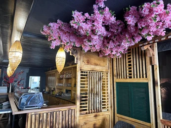 Ein japanisches Restaurant mit rosa Kirschblüten an der Decke über einem Holztresen im Inneren.
