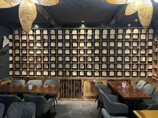 Wände mit leeren Bücherregalen, graue Stühle und Holztische in einem modern beleuchteten Raum.
