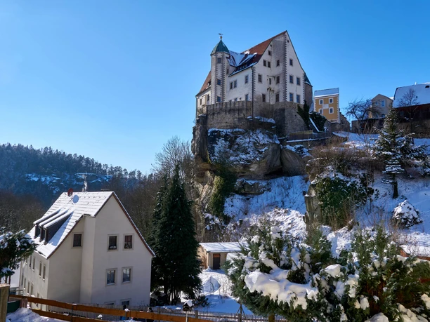 Burg Hohnstein Burg Hohnstein thront majestätisch auf einem schneebedeckten Felsvorsprung unter klarem Winterhimmel.