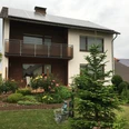 Fewo Güthoff aussen.jpg Zweistöckiges Haus mit Solarpaneelen, rotem Ziegel und Balkon, umgeben von gepflegtem Garten.