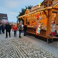 Weihnachtsmarkt Pr. Oldendorf Besucher flanieren über einen gepflasterten Weihnachtsmarkt mit beleuchteten Holzhütten und Dekoration.