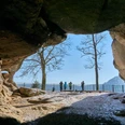 Kuhstall im Winter Winterliche Höhle mit Blick auf schneebedeckte Bäume und eine Gruppe von Menschen vor einem Zaun.Winter cave with a view of snow-covered trees and a group of people in front of a fence.Zimní jeskyně s výhledem na zasněžené stromy a skupinu lidí před plotem.Zimowa jaskinia z widokiem na ośnieżone drzewa i grupę ludzi przed ogrodzeniem.Wintergrot met uitzicht op besneeuwde bomen en een groep mensen voor een hek.Grotta invernale con vista su alberi innevati e un gruppo di persone davanti a una recinzione.