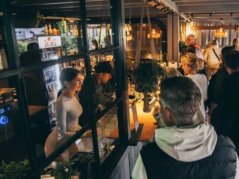 Menschen genießen eine gesellige Eröffnungsfeier in einer stilvollen Bar mit warmem Licht und Getränken.
