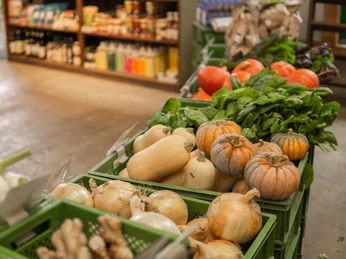 Bioland-Gärtnerei Duftgarten Hofladen Kisten mit frischem Gemüse und Kürbissen, umgeben von Regalen mit Naturprodukten in einem Hofladen.