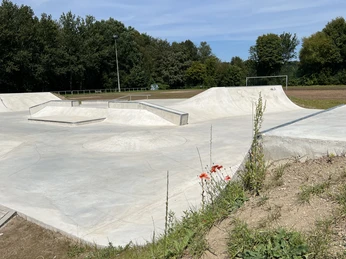 Skaterpark Much <p>Beton-Skatepark mit Rampen und Rails, umgeben von grüner Natur unter blauem Himmel.</p>