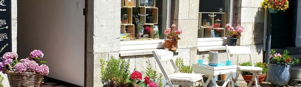 DasUrig_außen.jpg Steinfassade mit einem runden Tisch, zwei Stühlen und Blumenkästen davor.