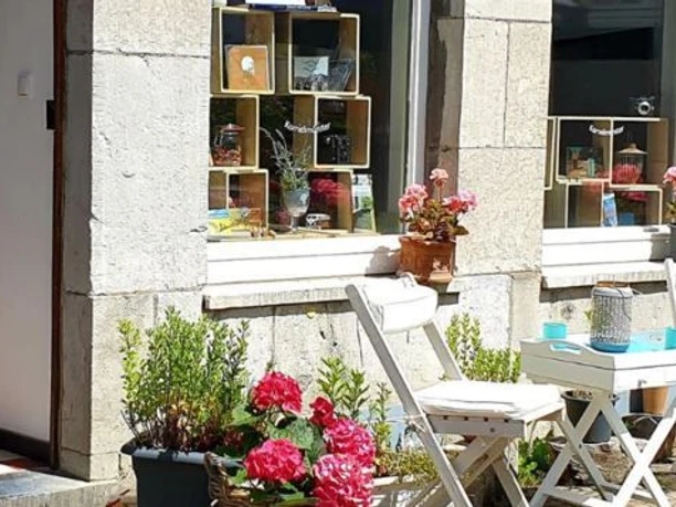 DasUrig_außen.jpg Steinfassade mit einem runden Tisch, zwei Stühlen und Blumenkästen davor.