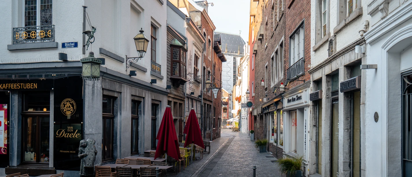Schmale Kopfsteinpflasterstraße mit Cafés und bunten Markisen.