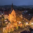 2022-12-03 Weihnachtsmarkt Borgholzhausen-2.JPG Luftaufnahme eines abendlichen Weihnachtsmarkts rund um eine beleuchtete Kirche im Dorfzentrum.