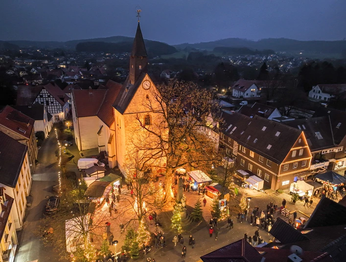 2022-12-03 Weihnachtsmarkt Borgholzhausen-2.JPG Luftaufnahme eines abendlichen Weihnachtsmarkts rund um eine beleuchtete Kirche im Dorfzentrum.