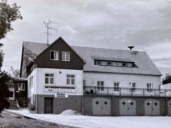Heymannbaude Schwarz-weiß-Foto eines zweistöckigen Gebäudes mit der Aufschrift "Betriebsferienheim" und "Öffentliche Gaststätte", umgeben von Bäumen.