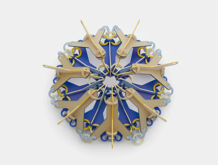 Svenja John, brooch "NOKOMIS" Bunte Brosche aus geometrischen Elementen, die sternförmig angeordnet sind auf grauem Hintergrund.Colorful brooch made of geometric elements arranged in a star shape on a grey background.