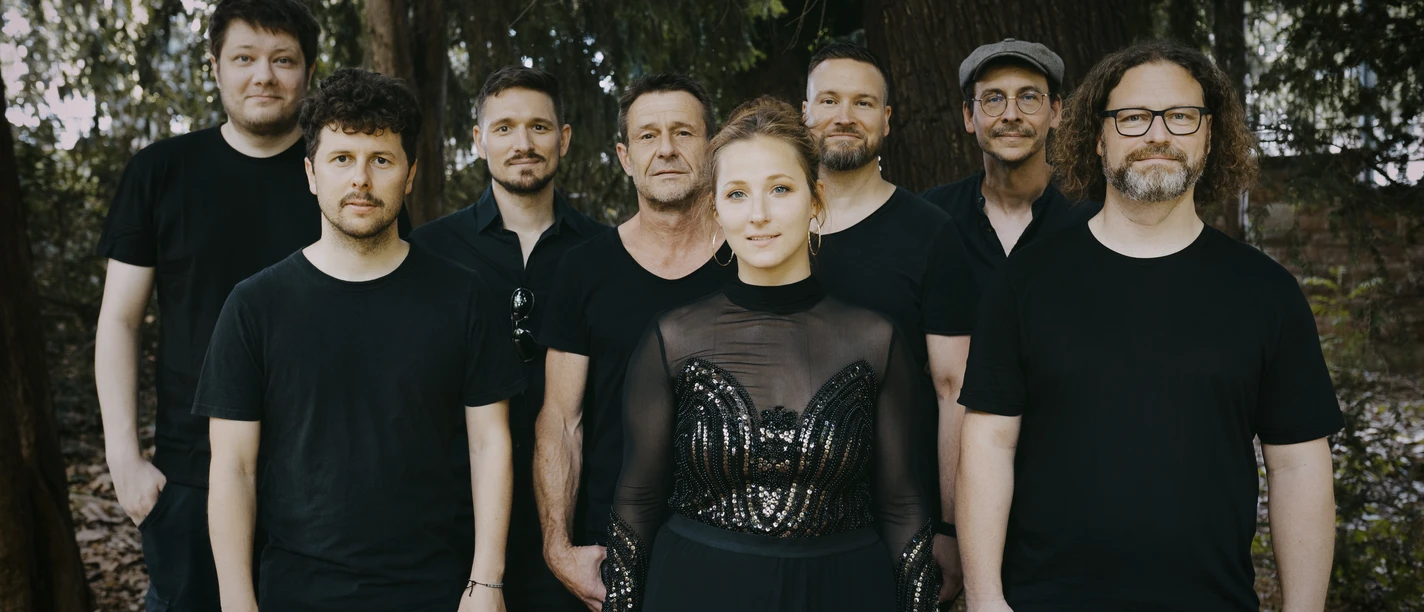 Leyla Trebbien & Band Musikgruppe steht im Wald zwischen hohen Bäumen