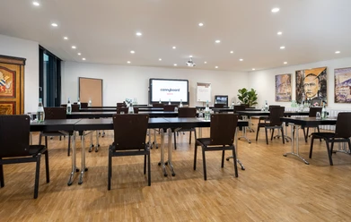 Babilon Saal Conference room with parliamentary seating, paintings on the walls and a TV