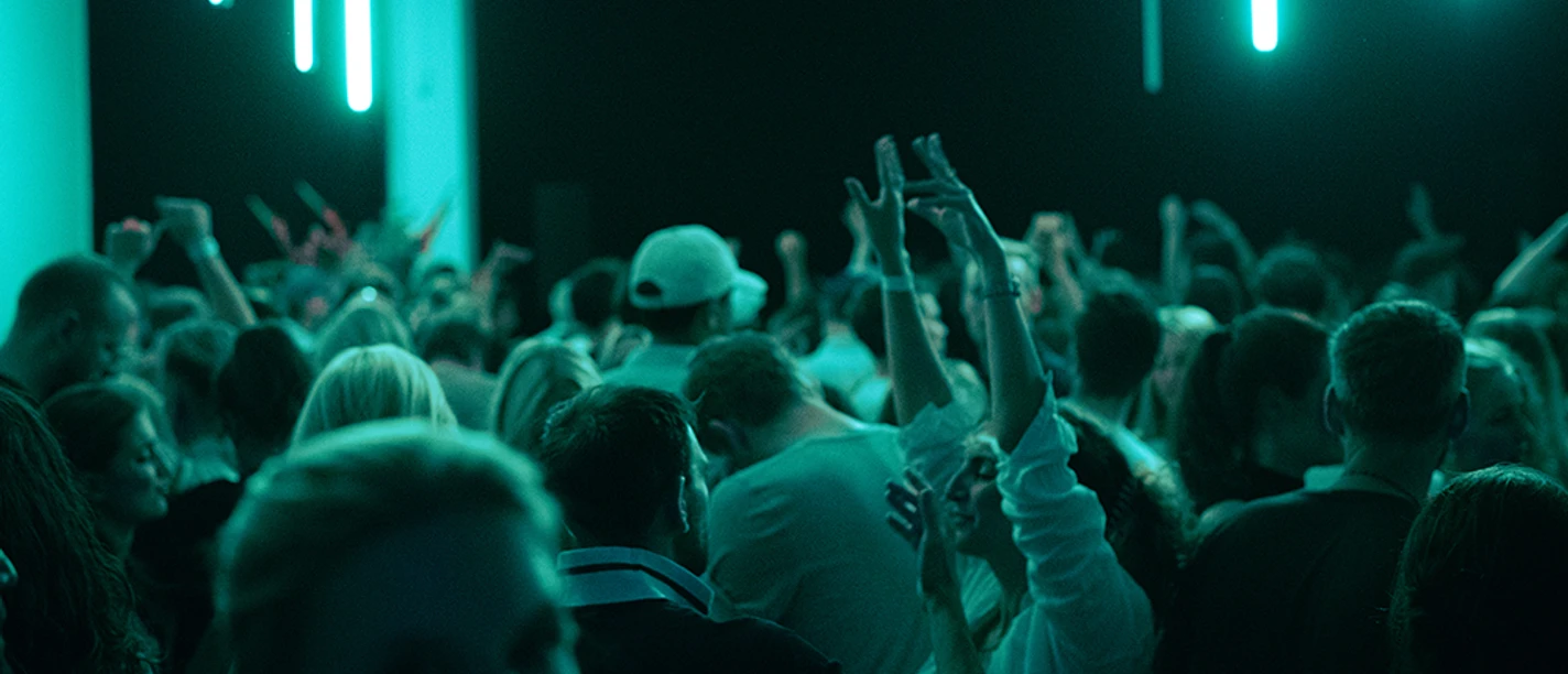 A large crowd is dancing in the neon-lit club.
