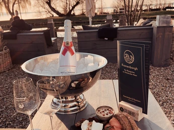 Kranenborgh - Champagner Eine Flasche Champagner in einem Eiskübel, begleitet von Gläsern und einem Teller mit Delikatessen.