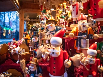 Verschiedene Nussknacker in weihnachtlichen Outfits stehen dicht beieinander auf einem Verkaufsstand.