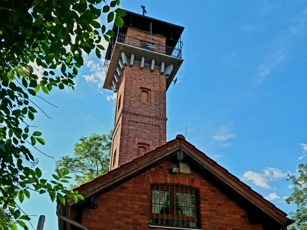 Der Schlossbergturm in Regenstauf Backsteinturm mit Aussichtsplattform über einem Vereinsgebäude vor blauem Himmel