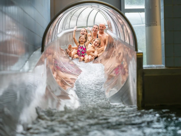 Erkrath Neanderbad Rutsche Fünf Personen rutschen fröhlich auf einer breiten Wasserrutsche im Neanderbad in Erkrath herunter.