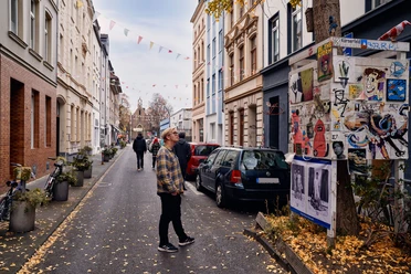 Körnerstraße Körnerstraße in Cologne-Ehrenfeld: Colorful houses, art posters on a tree, strolling passers-by.
