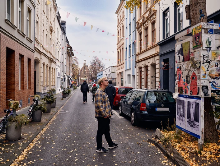 Körnerstraße Körnerstraße in Köln-Ehrenfeld: Bunte Häuser, Kunstplakate an einem Baum, schlendernde Passant*innen.Körnerstraße in Cologne-Ehrenfeld: Colorful houses, art posters on a tree, strolling passers-by.