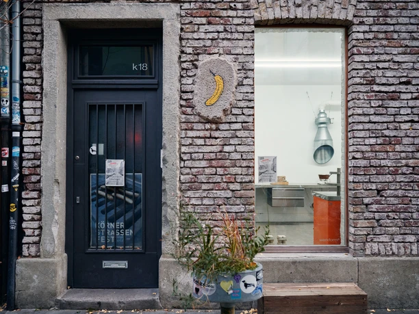 Körnerstraße Brick façade with glass door, planter and banana-shaped wall relief.