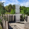 Teutoburger Wald-Dünenpfad-LTM GmbH-Linda Nasebandt Schwarz (2).jpg Holzplattform im Wald bietet Aussicht auf umliegende Bäume und Informationstafel über Dünenpfad.