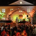 Weihnachtsmarkt Schloss Benkhausen Menschenmenge auf belebtem Weihnachtsmarkt vor beleuchtetem historischen Gebäude bei Nacht.