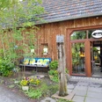 Galerie Sattelgut Gemütliches Fachwerkgebäude mit Holzdach und großen Fenstern, umgeben von grüner Vegetation.