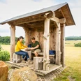 Holzüberdachte Raststätte im Teutoburger Wald mit zwei Personen beim Picknick, umgeben von Natur.