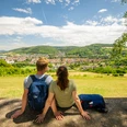 l-gde-osterberg-teutoburger-wald-tourismus-d-ketz-057-jpg.jpg Zwei Personen sitzen auf einer Bank und blicken auf die grüne Landschaft und die Stadt im Teutoburger Wald.