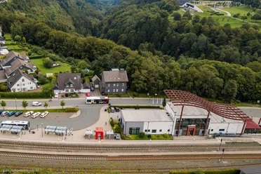 Drohnenaufnahme des Winterberger Bahnhofs mit Parkplatz und Bahngleisen.