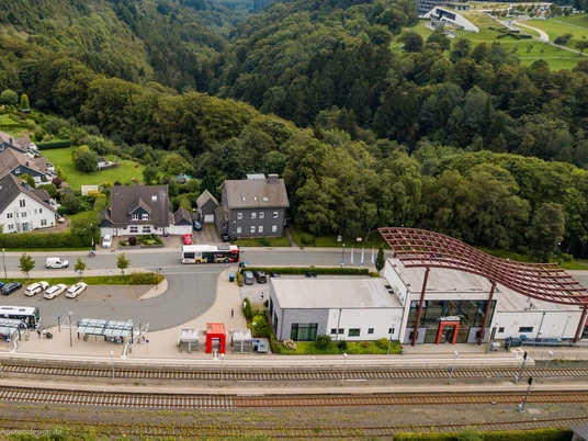 Drohnenaufnahme des Winterberger Bahnhofs mit Parkplatz und Bahngleisen.