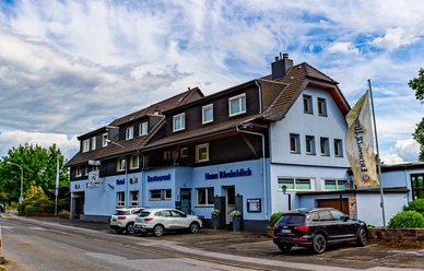 Haus Rheinblick Ott, Monheim am Rhein Dreistöckiges Gästehaus mit Parkmöglichkeiten, blau-weißer Fassade und Eifeler-Landbier-Schild.
