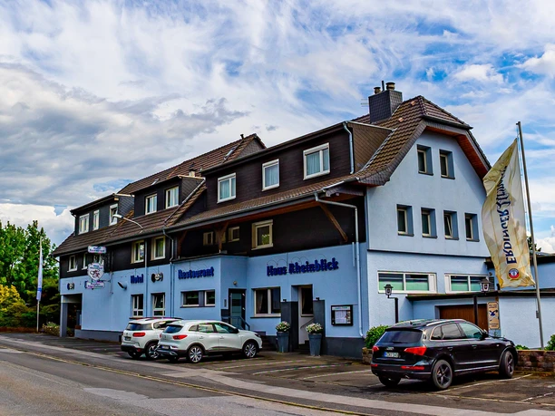 Haus Rheinblick Ott, Monheim am Rhein Dreistöckiges Gästehaus mit Parkmöglichkeiten, blau-weißer Fassade und Eifeler-Landbier-Schild.