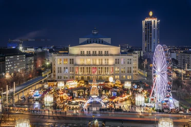 View of the brightly lit Augustusplatz with the fairytale forest and Ferris wheel in the evening with the opera in the background