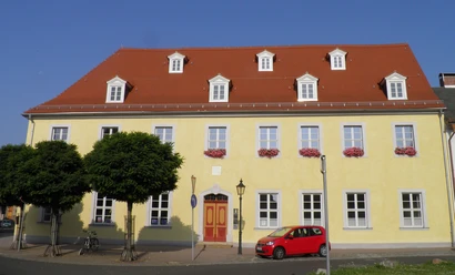 Infopoint und Bibliothek im Napoleonhaus Pegau Das Bild zeigt die gelbe Front des Napoleonhauses, welche unter anderem die Tourist-Information beherbegt.