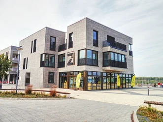 Na obrázku je moderní turistické informační centrum Zwenkau zvenku, za nímž je vidět přístav na jezeře Zwenkau.
