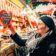 Weihnachtsmarkt auf dem Naschmarkt - Weihnachten in Leipzig Eine Frau steht vor einem Lebkuchenstand auf dem Leipziger Weihnachtsmarkt und greift nach einem Lebkuchenherz